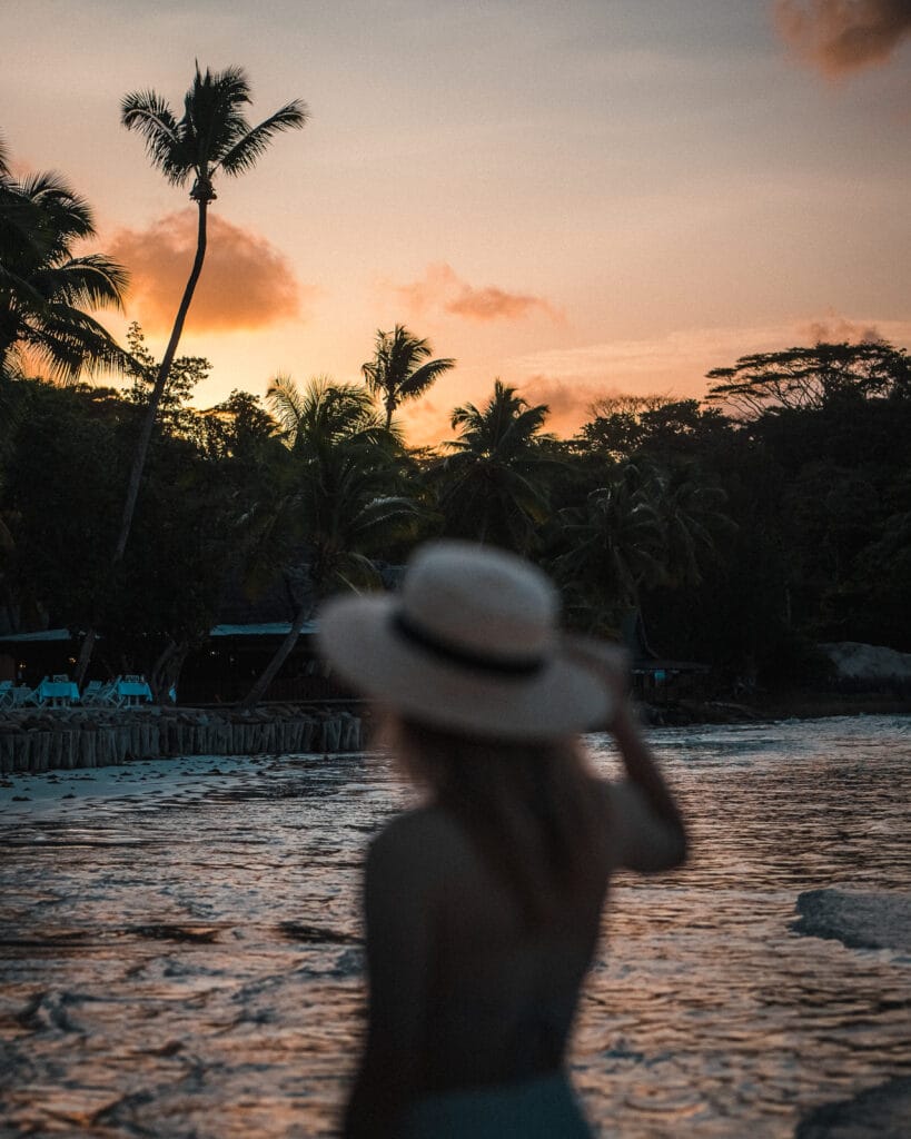 Woman standing on Anse Volbert beach at sunset on Praslin Island