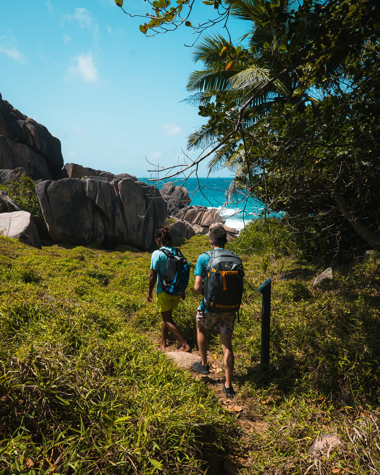 Two men hiking along a trail on the coast of La Digue, Seychelles