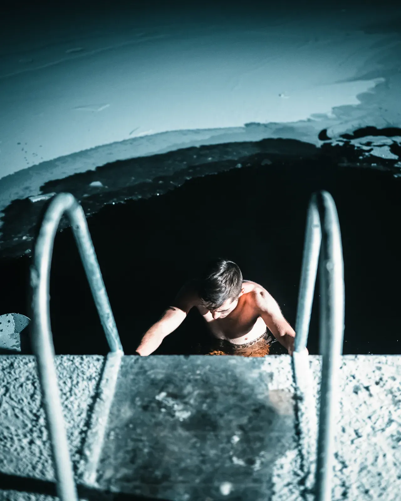 Man climbing down ladder into frozen lake at Apukka Resort, Lapland