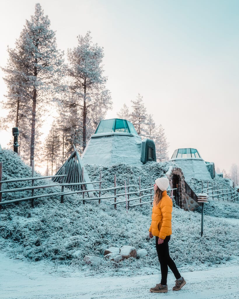 Woman standing outside of Kammi Suite in the snow at Apukka Resort, Lapland