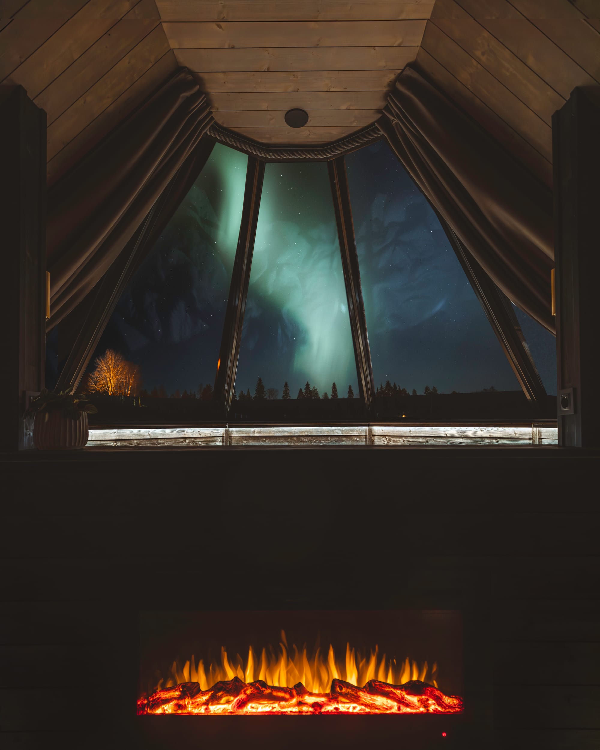 Interior of Apukka resort cabin with northern lights through the window in Lapland