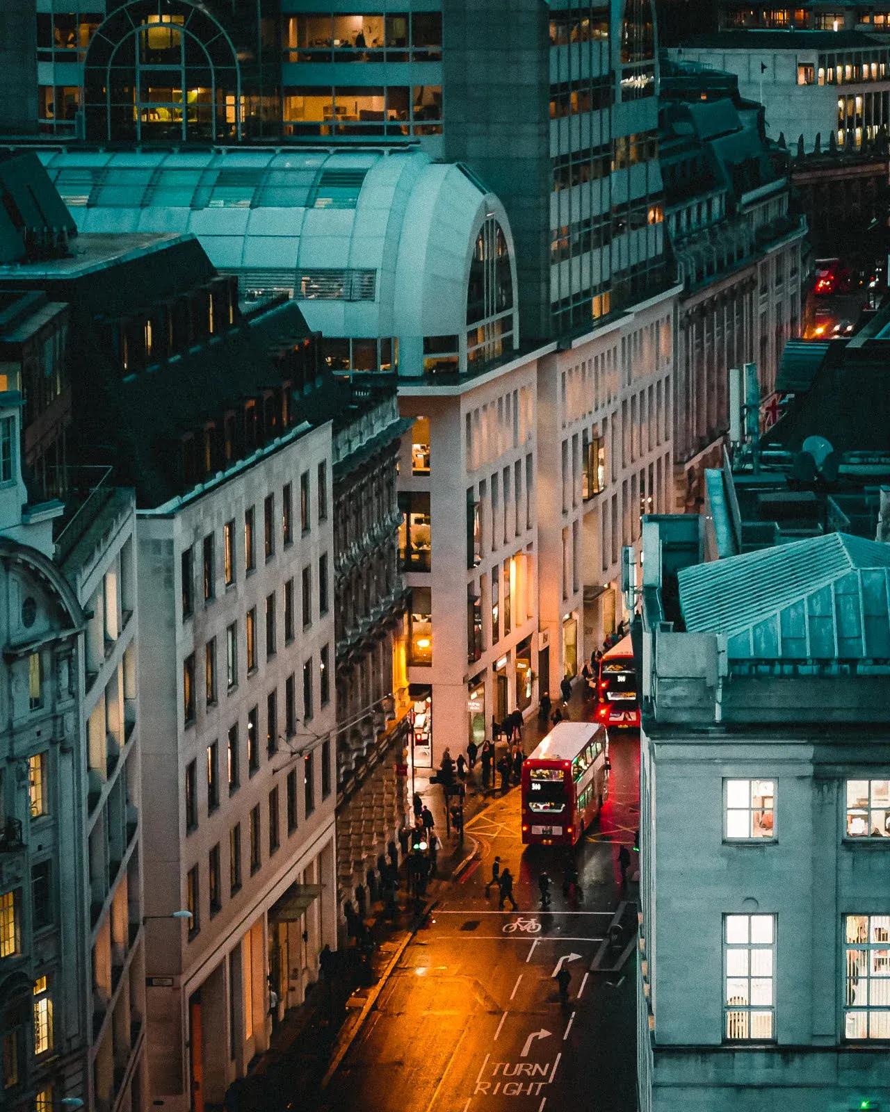 Red buses on a London street at night from the Monument tower viewpoint in London