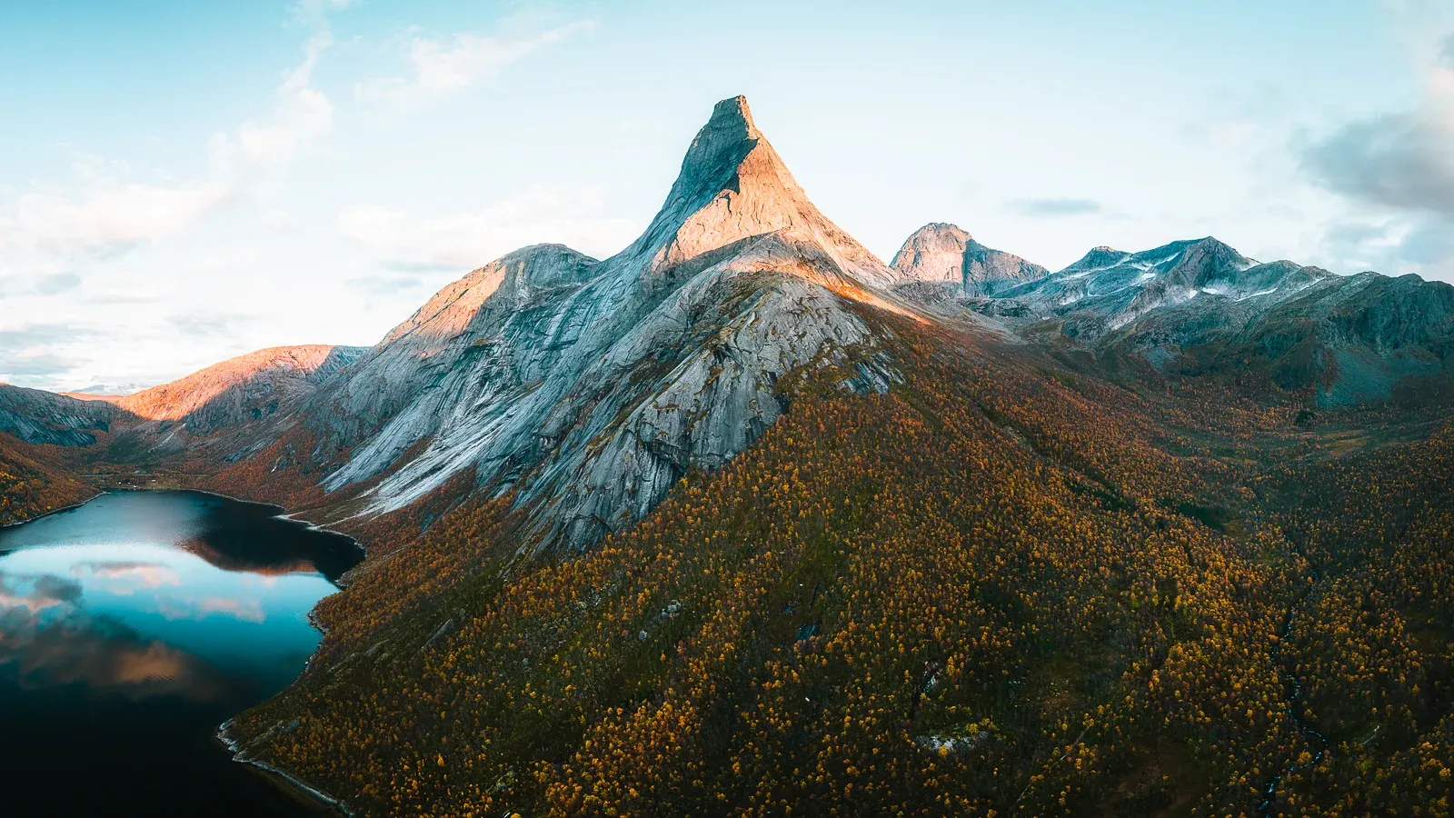 Panoramic aerial view of Stetind mountain at sunset surrounded by autumn trees in Norway