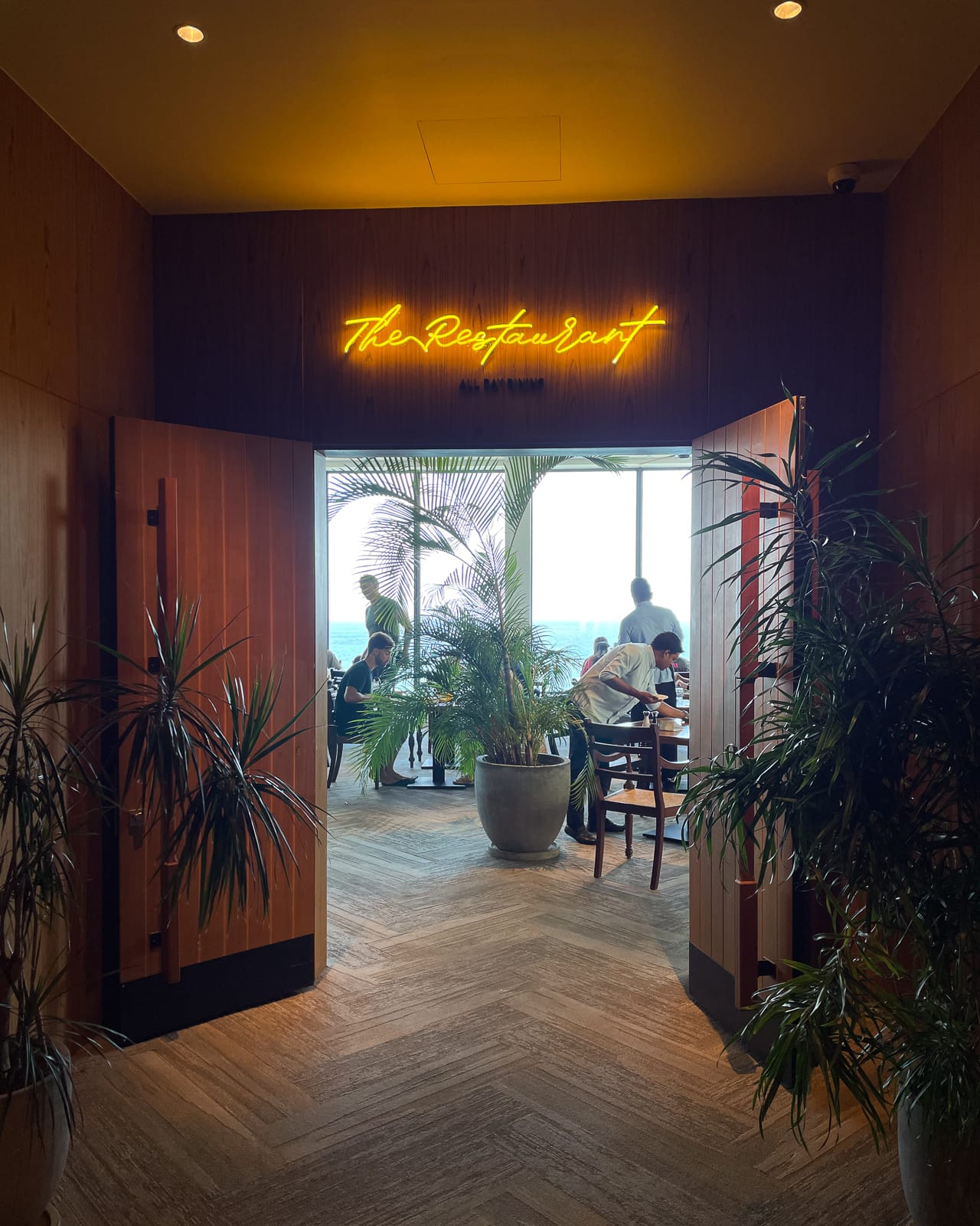 doors opening into seating area with a neon sign titled 'the restaurant'