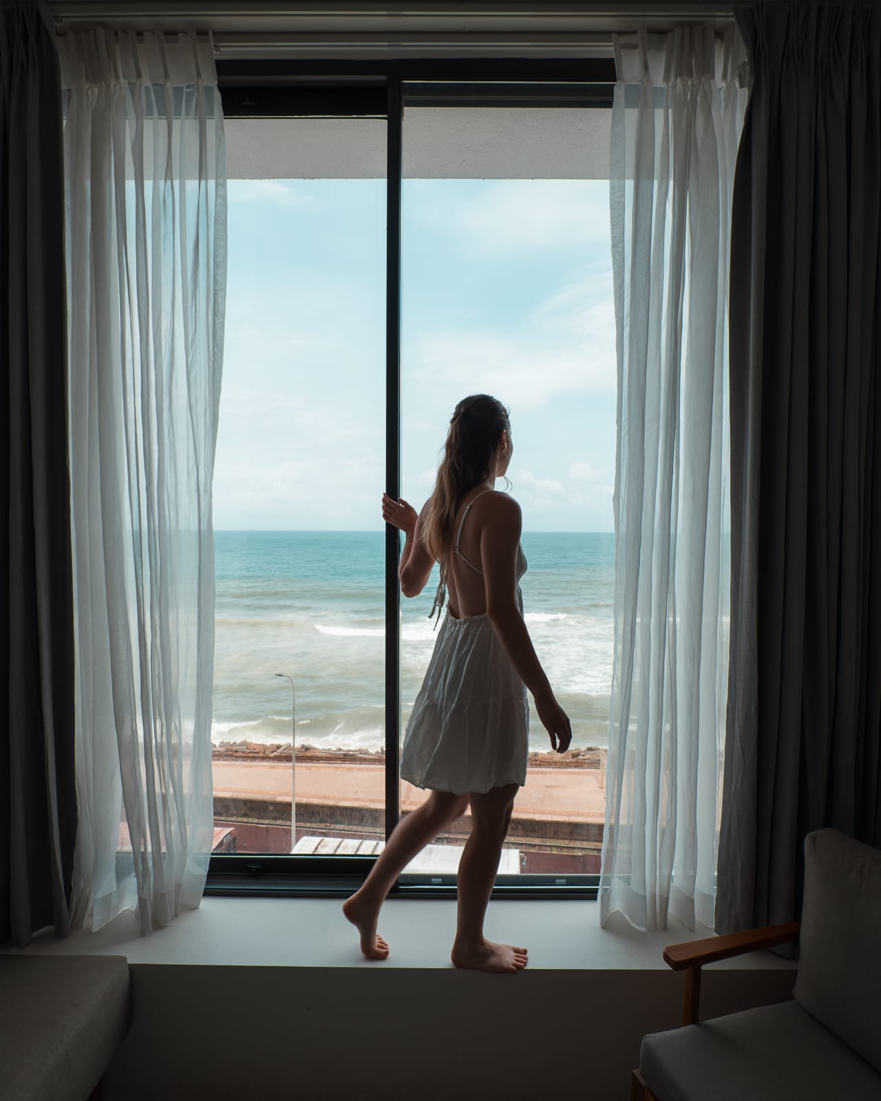 woman standing in window looking out to ocean