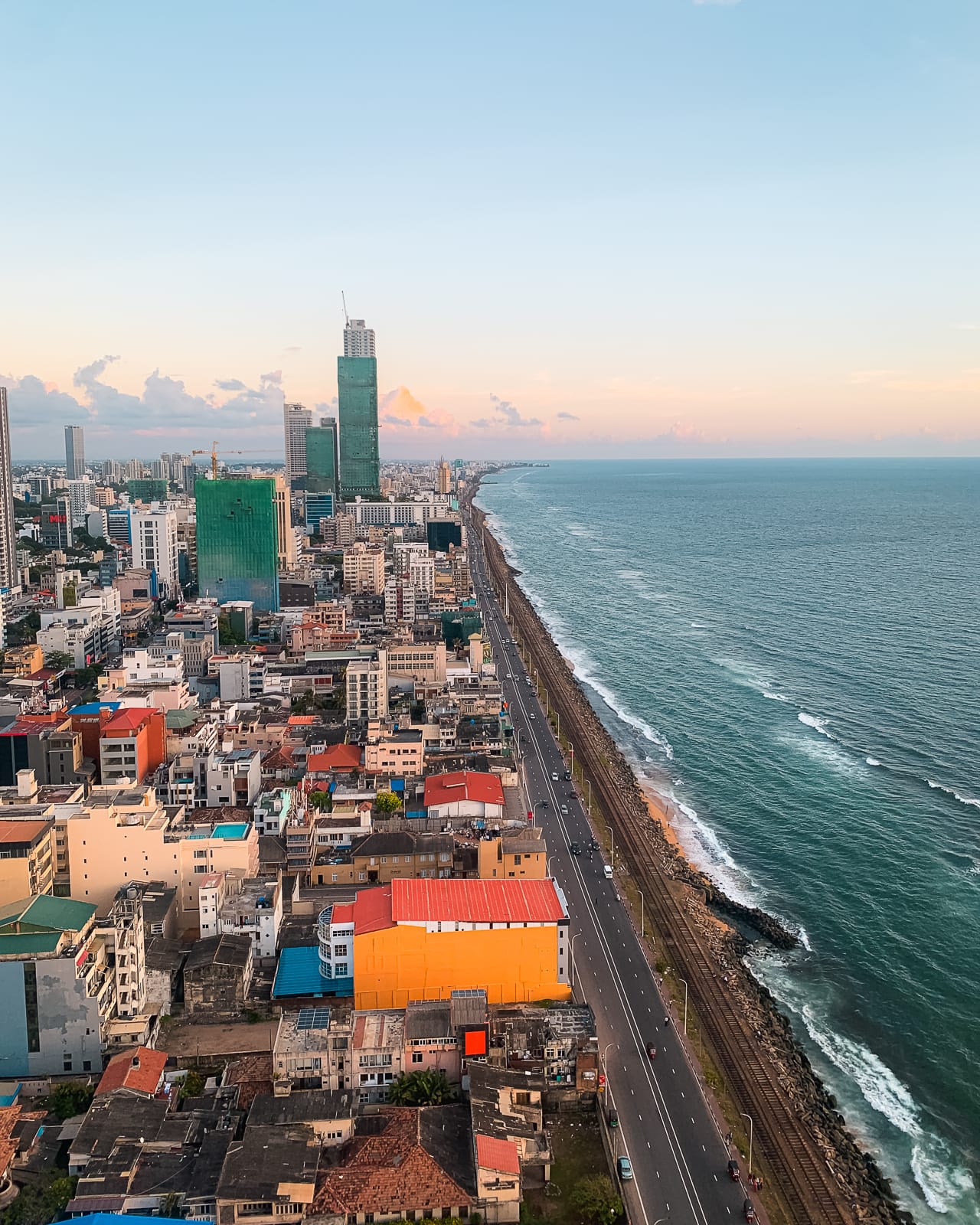 tall buildings next to a road and ocean