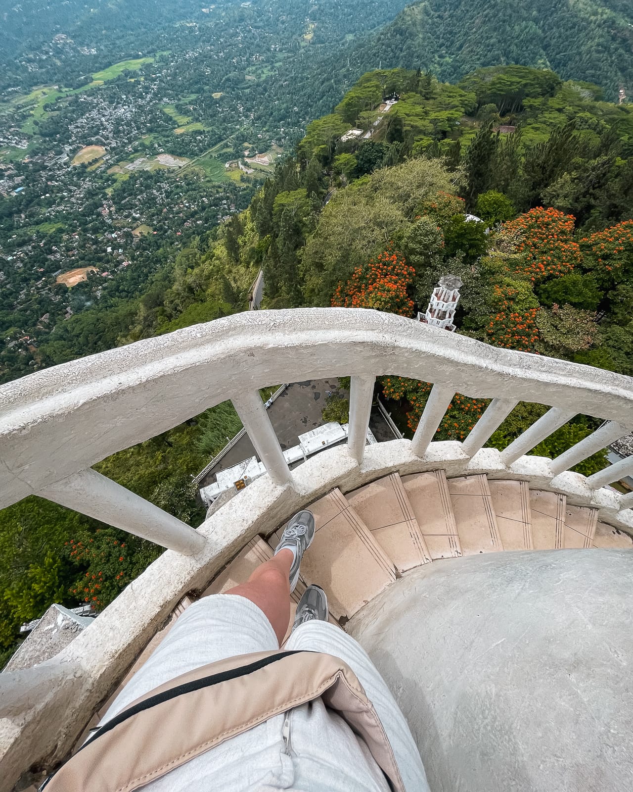 POV perspective of person walking down narrow staircase of Ambuluwawa tower with a view of the mountains below