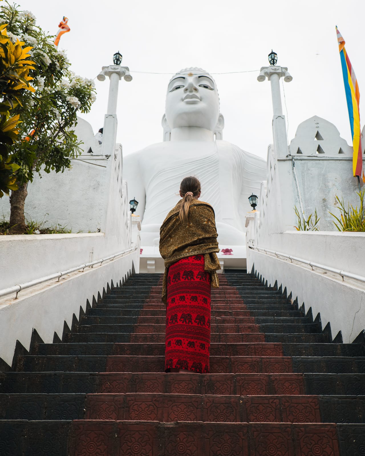 woman standing on stairs below a white buddah