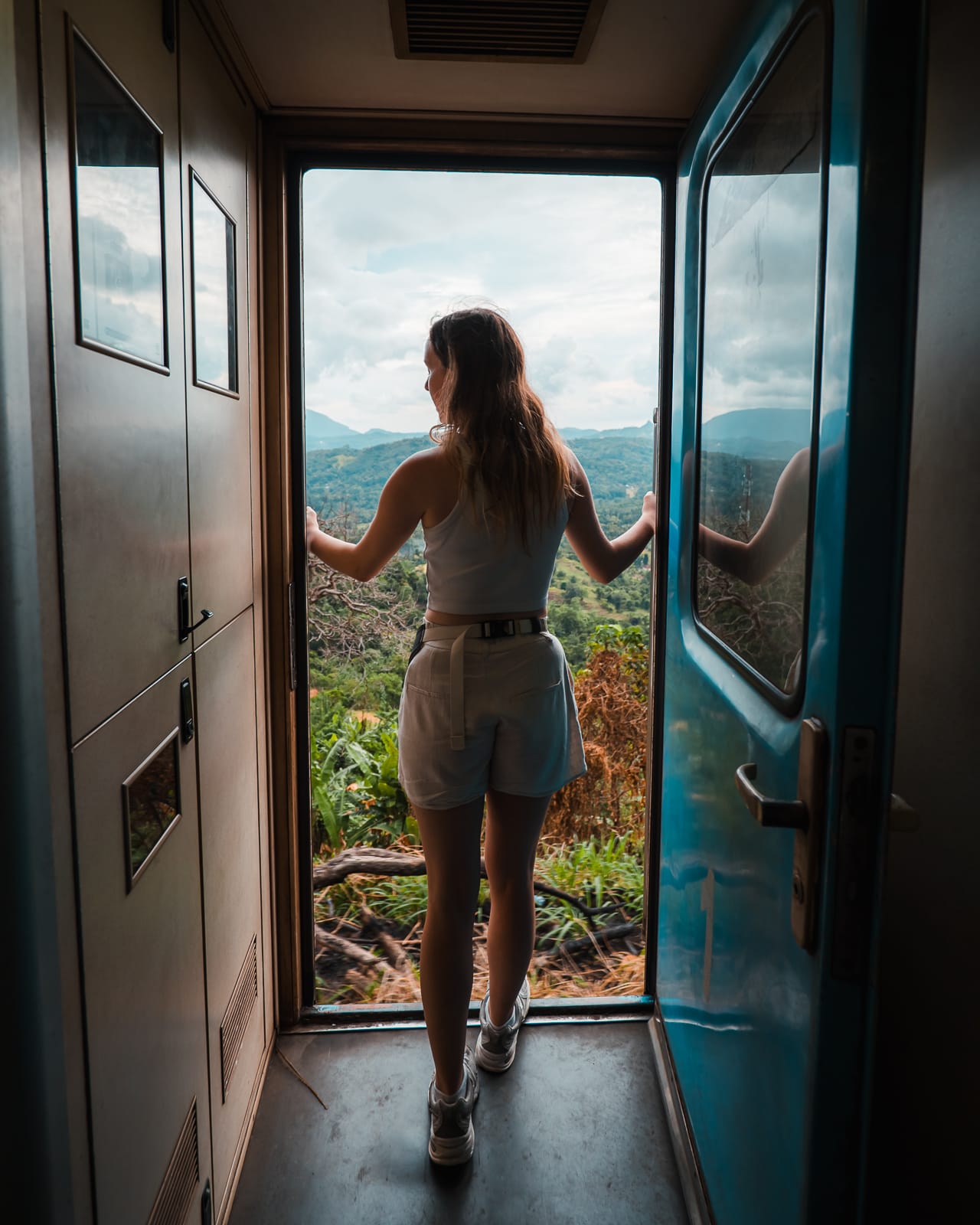 woman standing and looking out of open train door in sri lanka