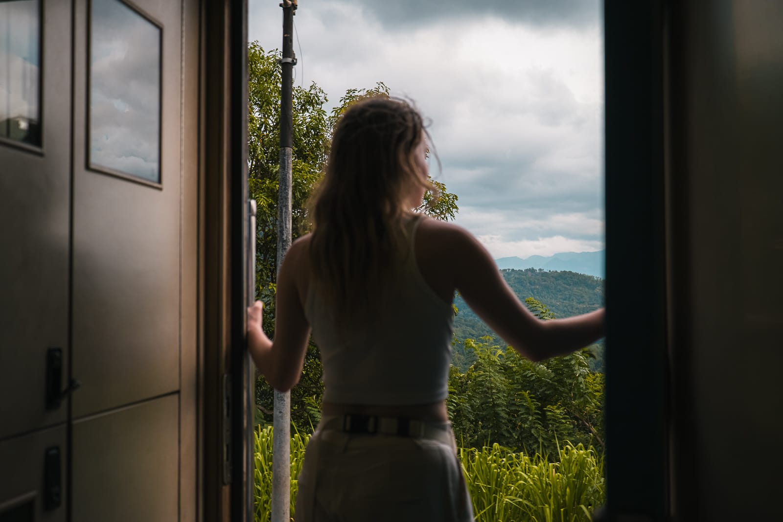 woman standing and looking out of open train door in sri lanka