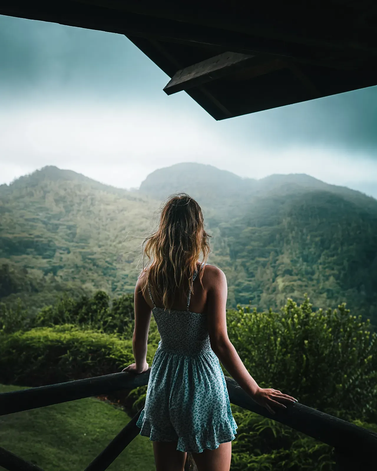 Woman standing on a balcony looking at mountains in Mahe, seychelles