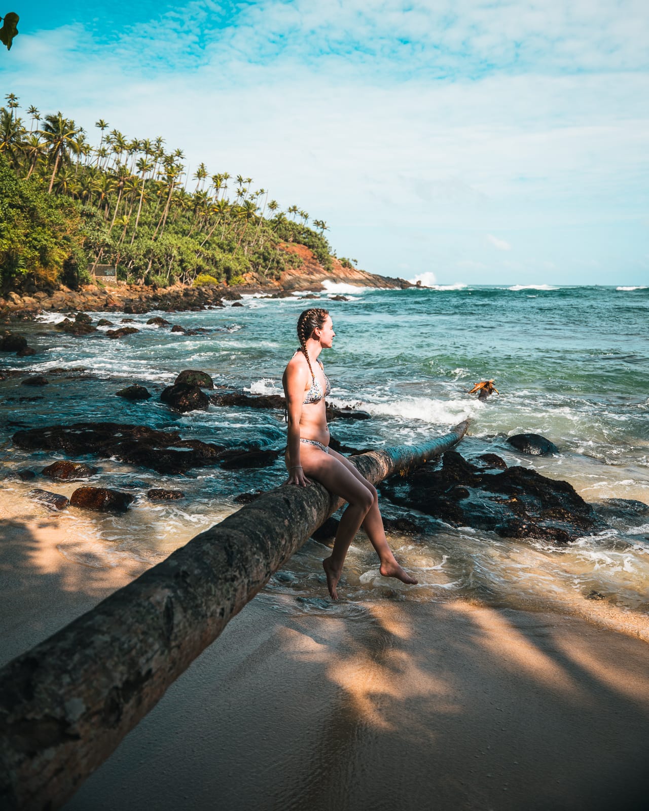 Woman sitting on palm tree at Secret Beach in Mirissa, Sri Lanka