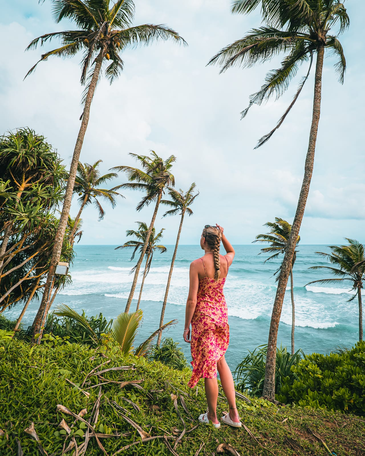 Woman standing infront of palm trees and ocean at Coconut Tree Hill in Mirissa, Sri Lanka