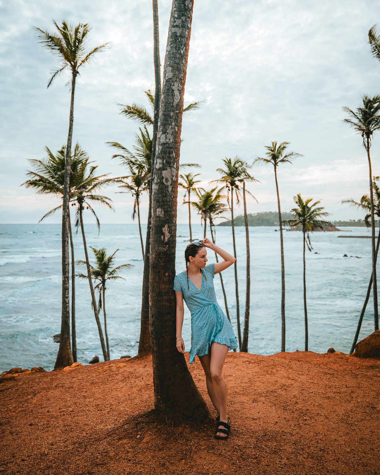 Woman standing infront of palm trees and ocean at Coconut Tree Hill in Mirissa, Sri Lanka