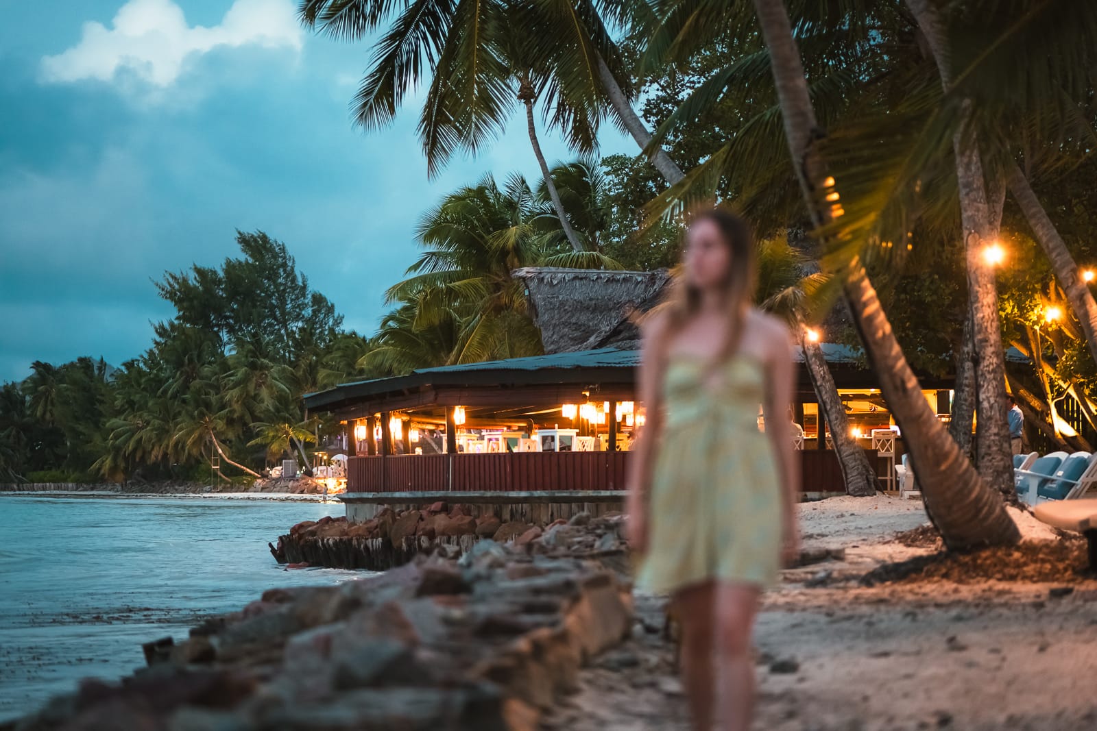 woman walking on beach with restaurant in background