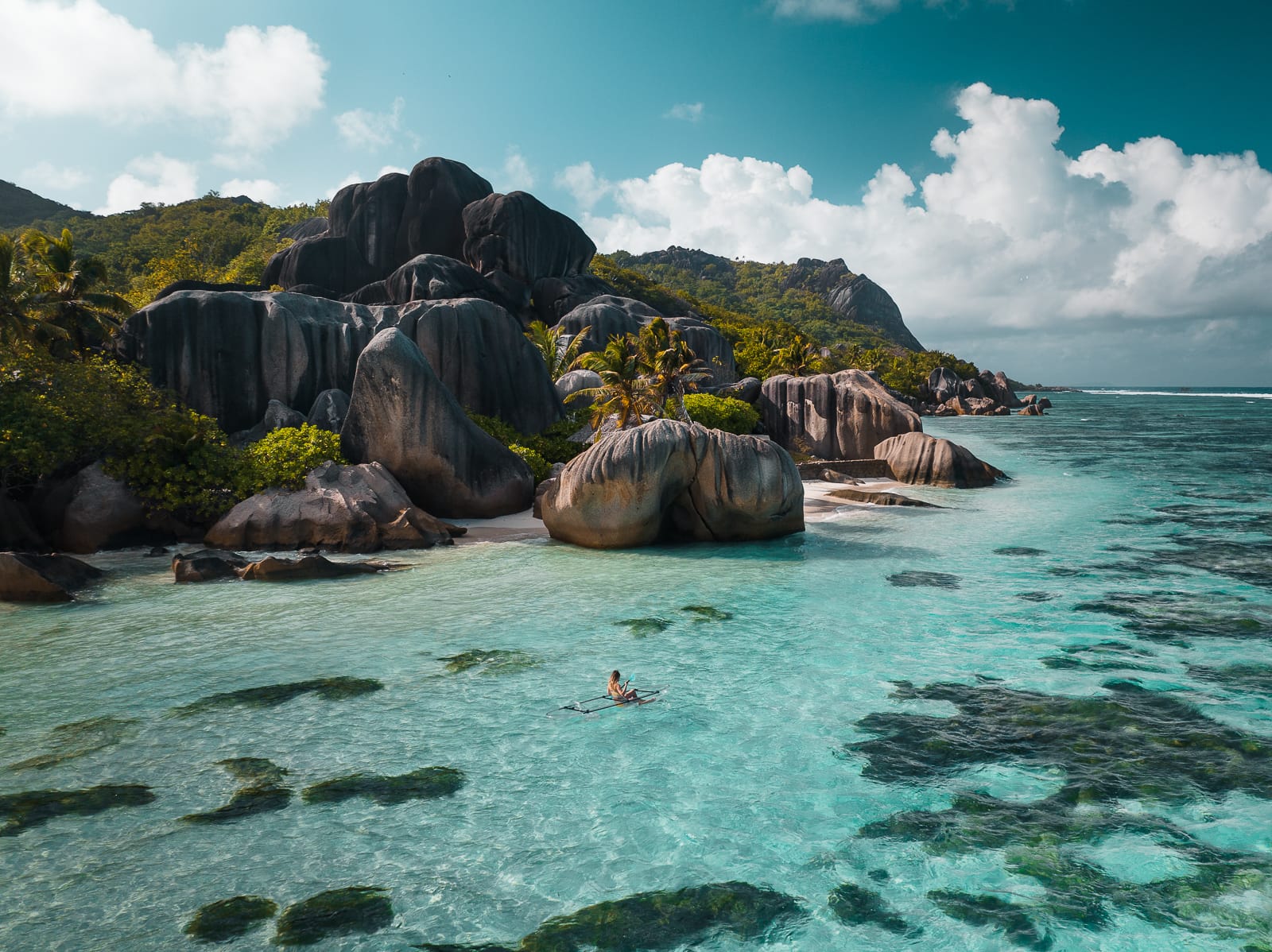 person kayaking in turqoise water in la digue, seychelles