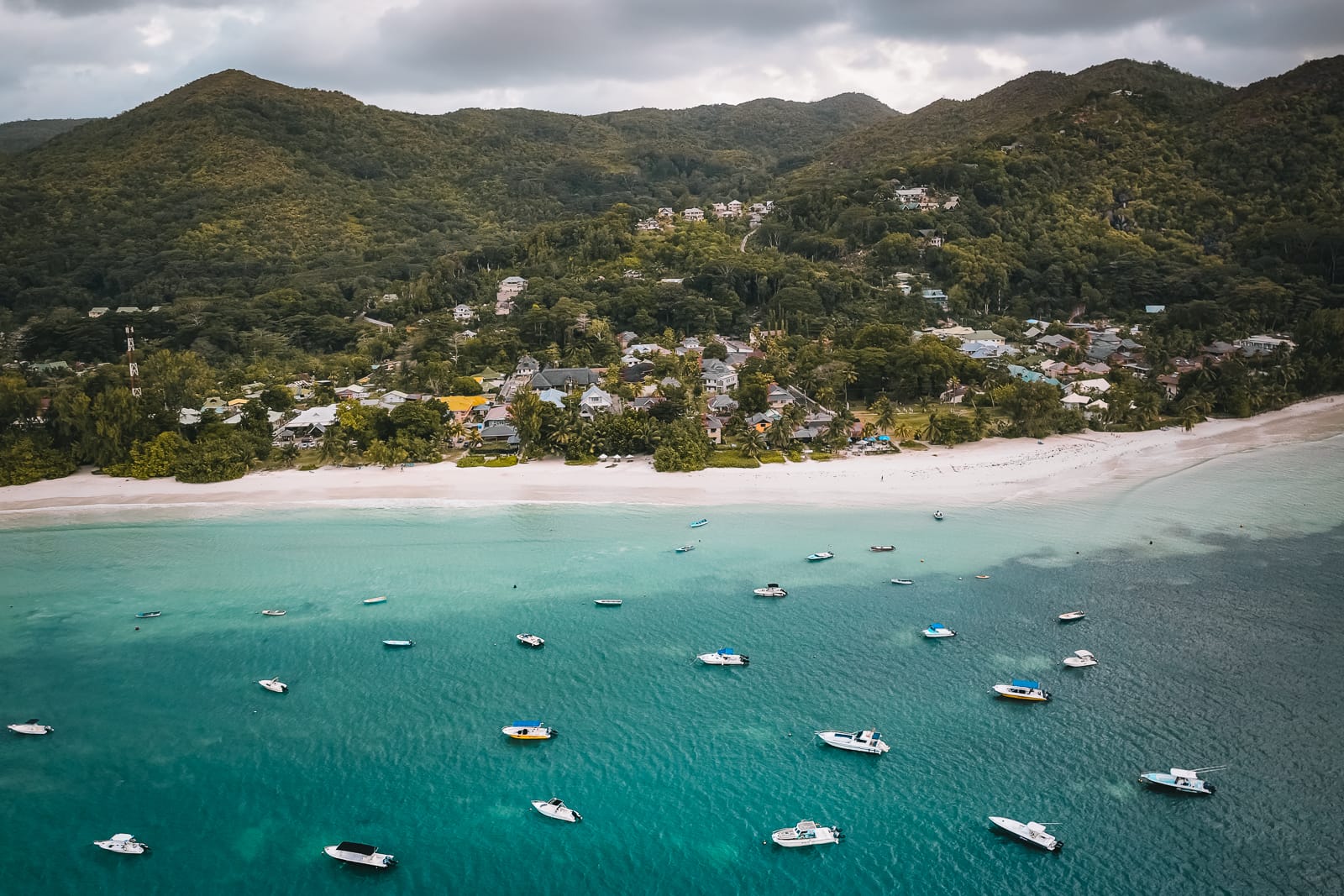 sandy beach with mountains in background and boats in ocean