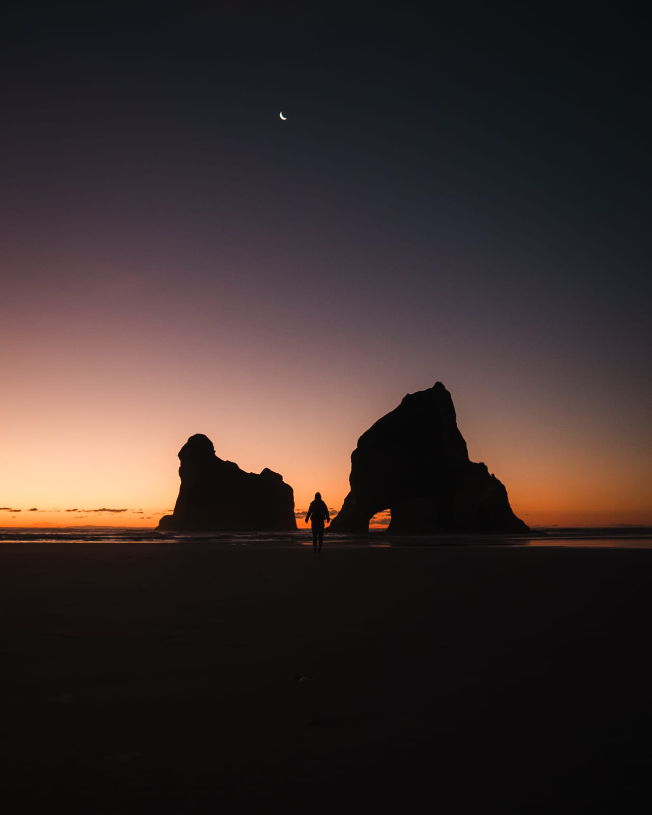 woman standing on wharariki beach at sunset