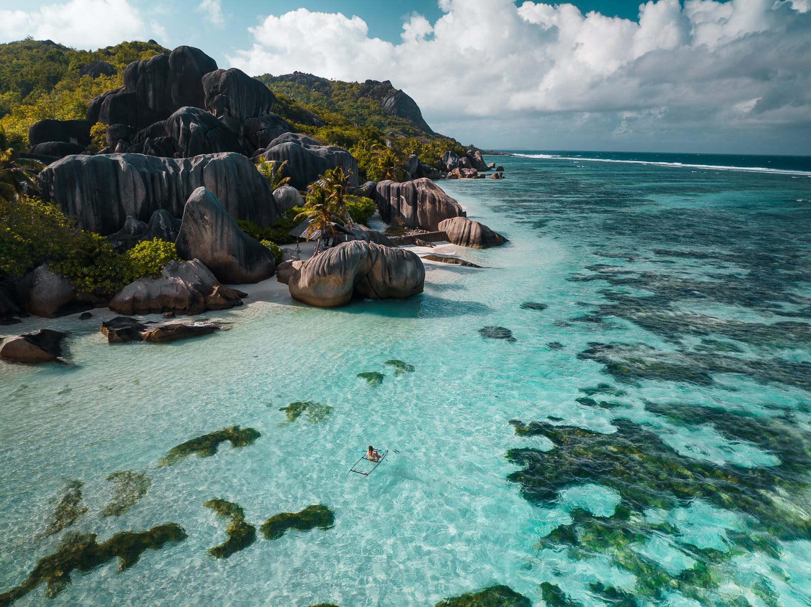 Aerial pview of transparent kayak floating in clear blue water at Anse Sorce d'Argent beach in La Digue, Seychelles