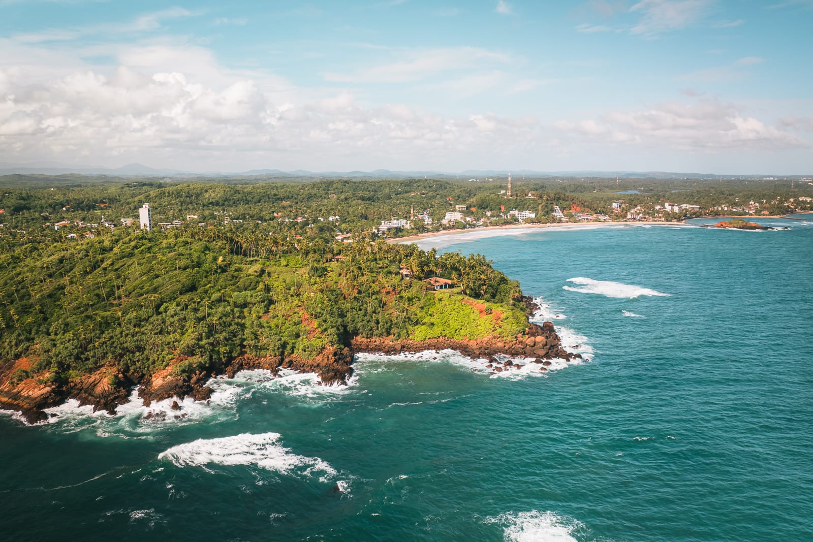 Aerial drone view of cliffs, palm trees, the ocean and beach in Mirissa, Sri Lanka 