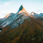 Panoramic aerial view of Stetind mountain at sunset surrounded by autumn trees in Norway